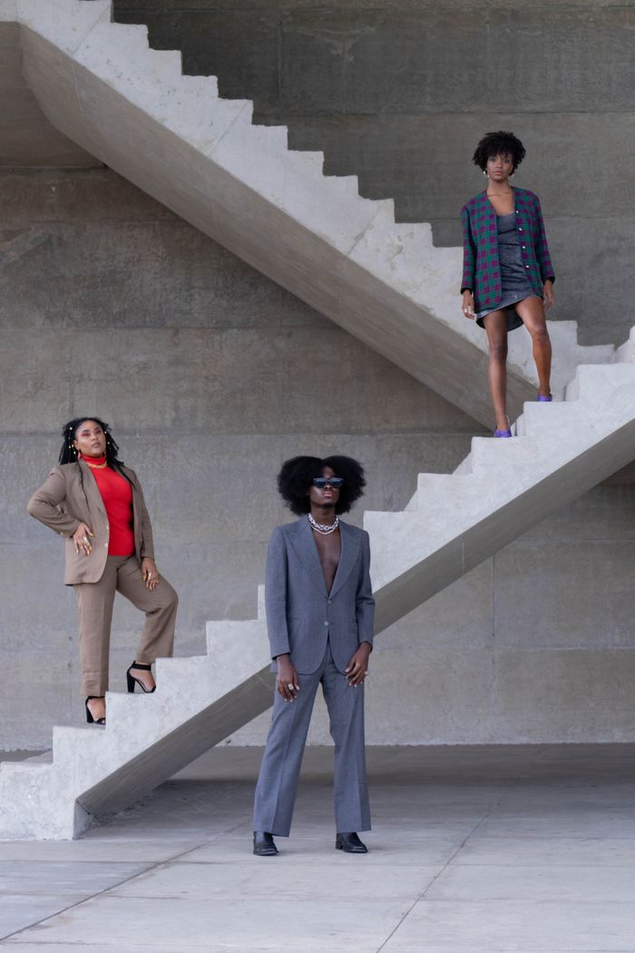 Home Three stylish people in modern outfits standing on geometric concrete stairs.